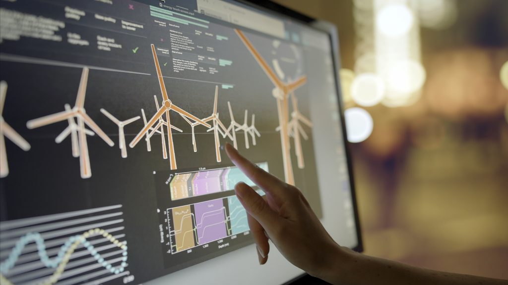Woman’s hand interacting with a touchscreen monitor displaying data.